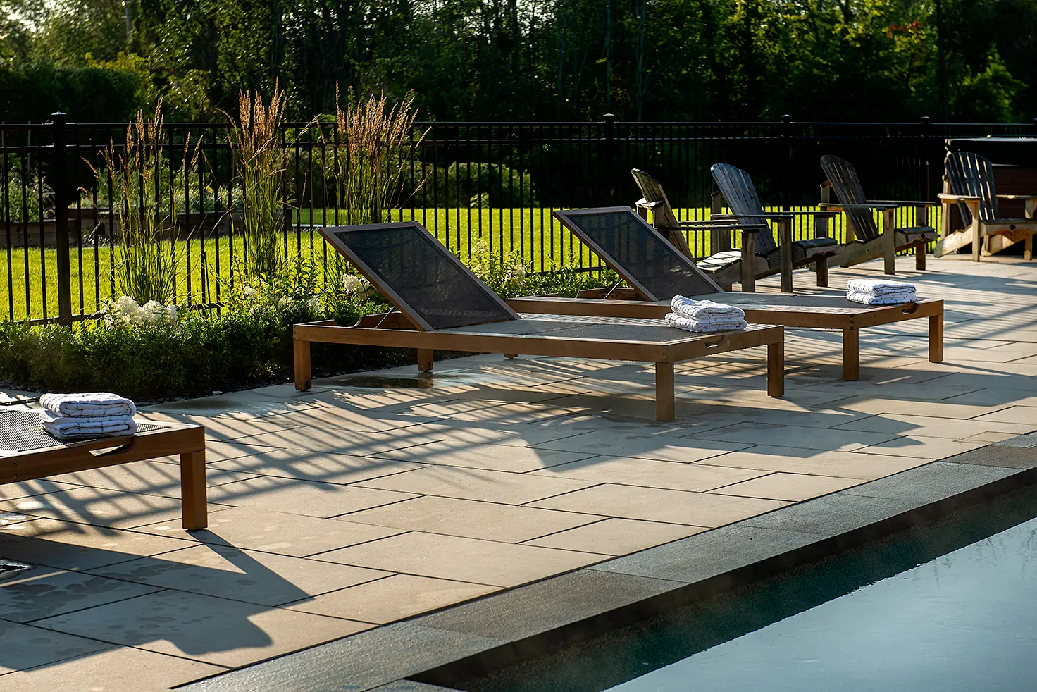 Chaises longues au bord de la piscine, sur de grands pavés